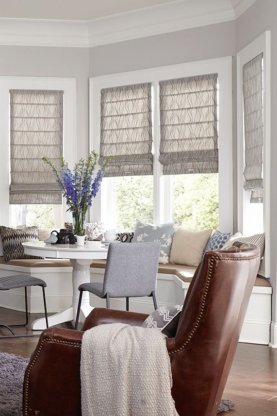 a living room filled with furniture and windows covered in shades of grey, brown and white