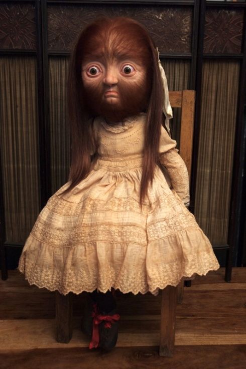 a creepy doll sitting on top of a wooden chair