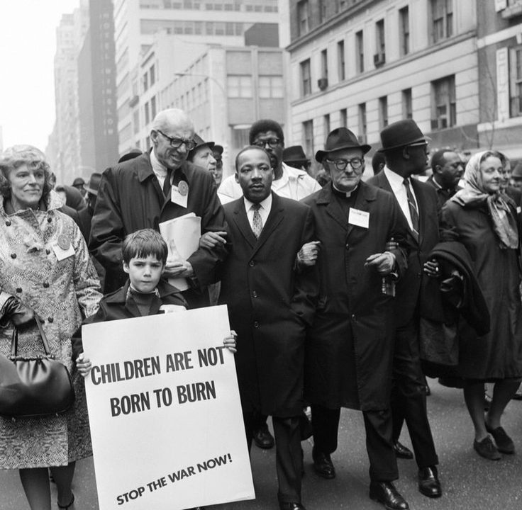 a group of people walking down the street with signs in front of them that read children are not born to burn