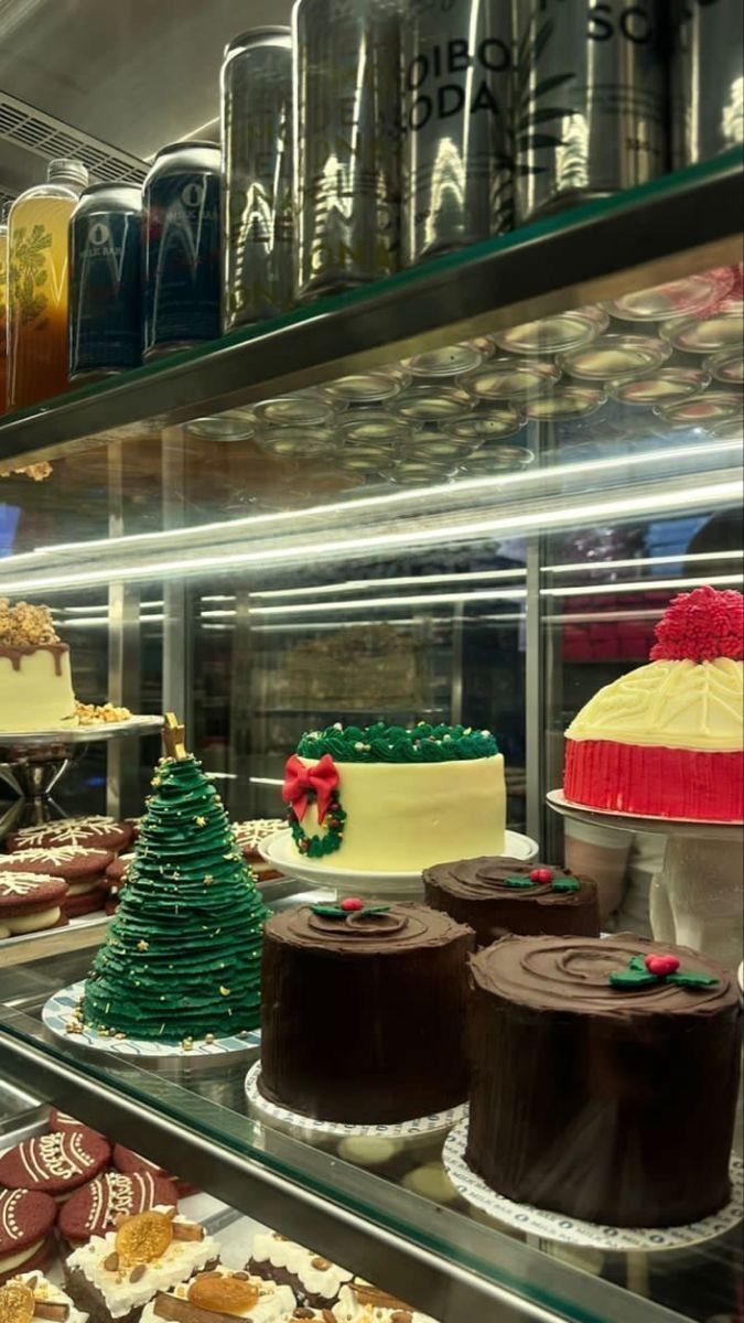 many cakes and pastries are on display in a bakery case with glass shelves filled with frosting