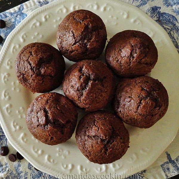 a white plate topped with chocolate muffins on top of a blue and white cloth