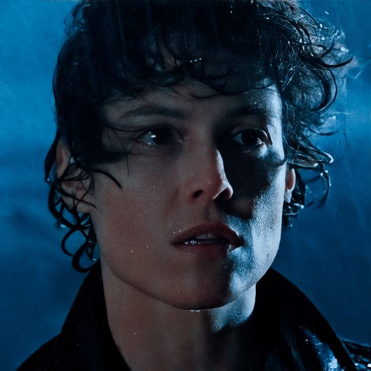 a close up of a person with dark hair and water on his face, in front of a blue background