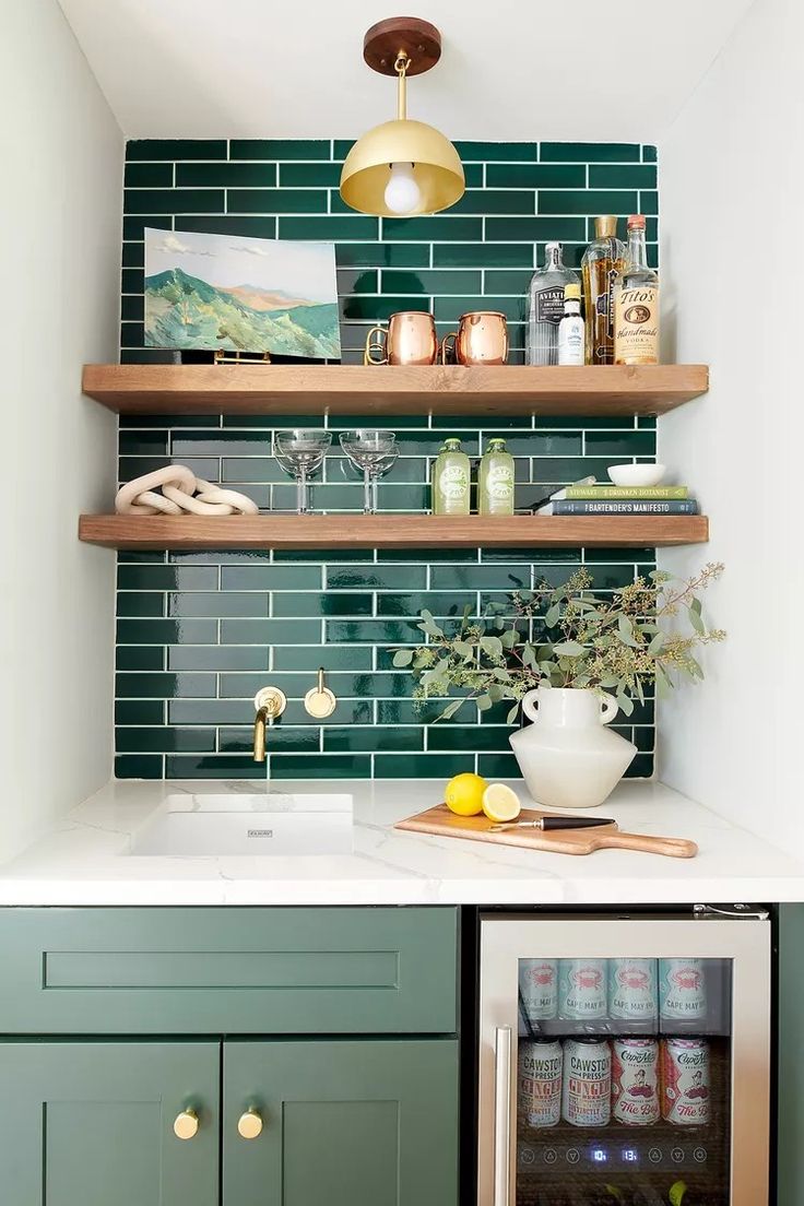 a kitchen with green tiles and shelves above the sink, below is a white marble countertop