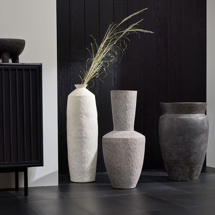 three vases sitting next to each other on a black floor