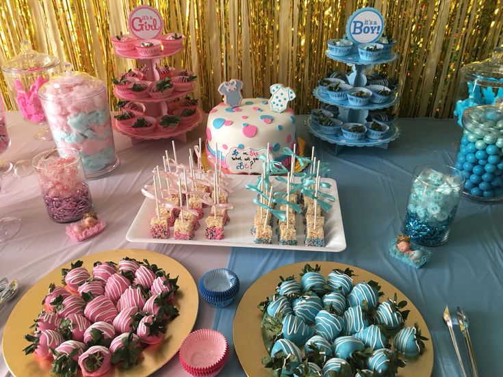 there are many desserts on the table with blue and pink decorations, including strawberries