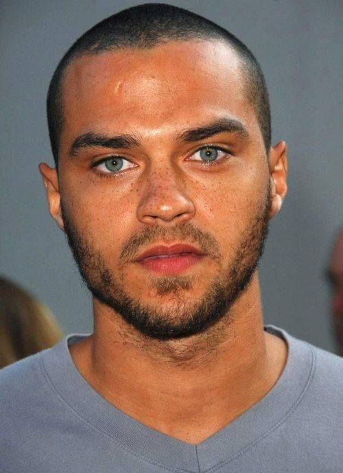 a close up of a person wearing a gray shirt and blue eyes with a beard