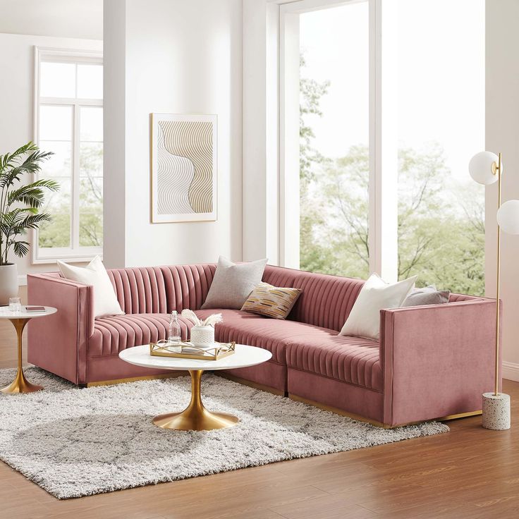 a living room with pink velvet couches and white rugs on the hardwood floor