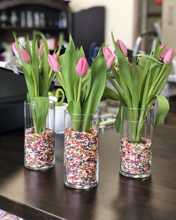 three vases filled with pink tulips and sprinkles on a table