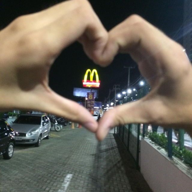 two hands making a heart shape in front of a mcdonald's