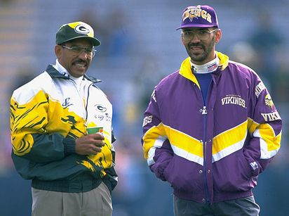 two men standing next to each other in front of a crowd at a football game