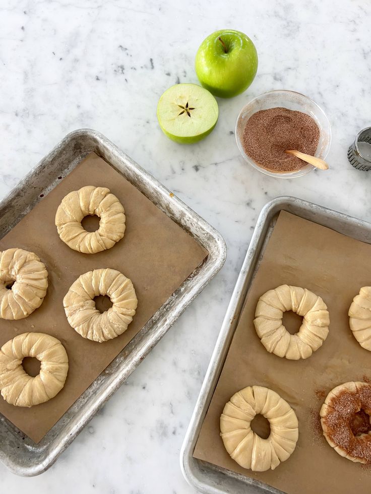 doughnuts on baking pans with apples in the background