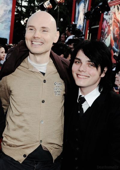 two people standing next to each other on a red carpet