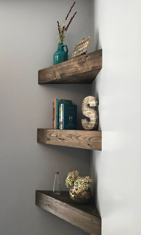 three wooden shelves with books and vases on them in a corner area next to a wall