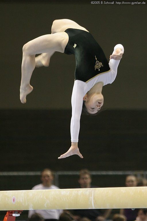 a person on the balance beam doing an acrobatic trick