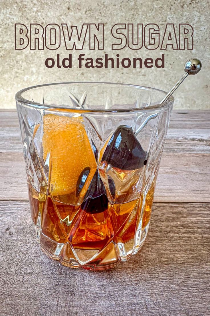 an old fashioned glass filled with brown sugar and orange peels sitting on top of a wooden table