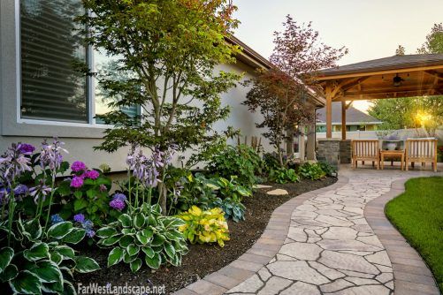 an outdoor patio with stone walkway and landscaping