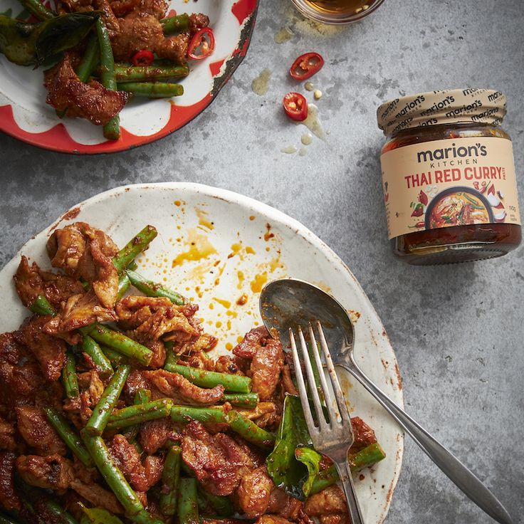 a plate full of chicken and green beans next to a jar of mustard