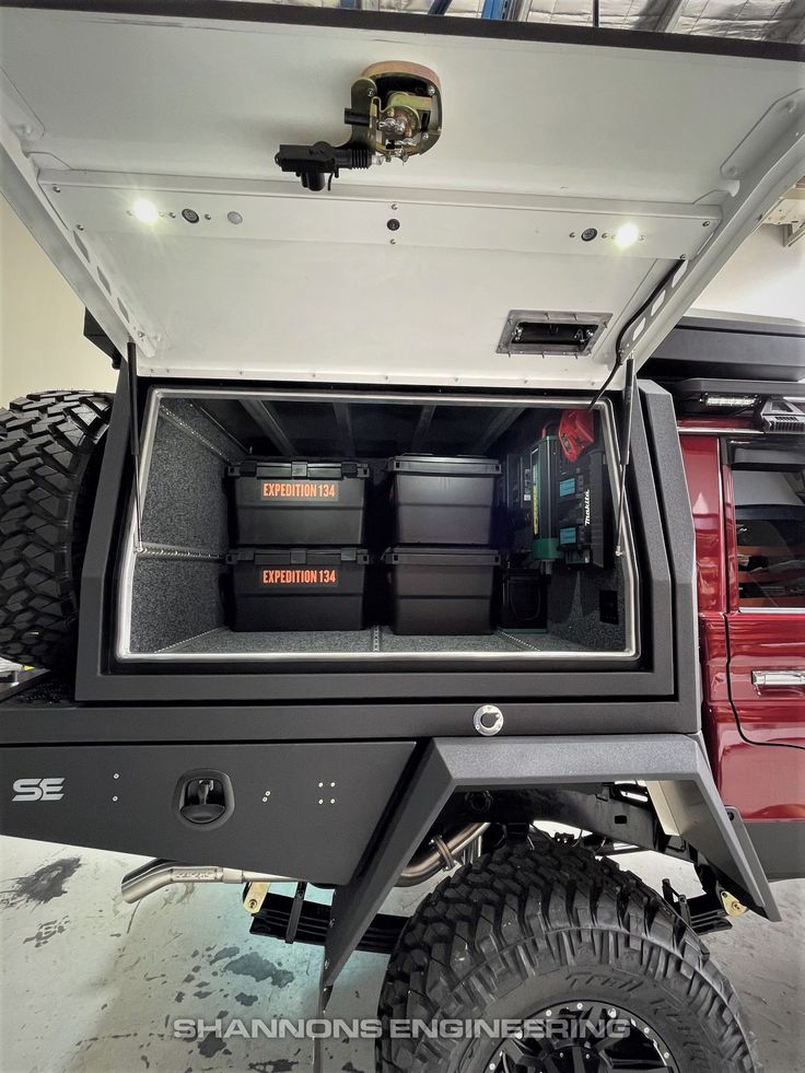 the back end of a red truck with its doors open and two large tires on it