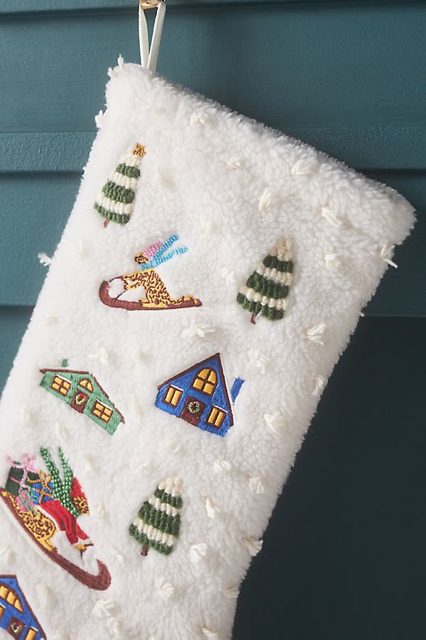 a christmas stocking hanging from a hook on a blue house with trees and houses