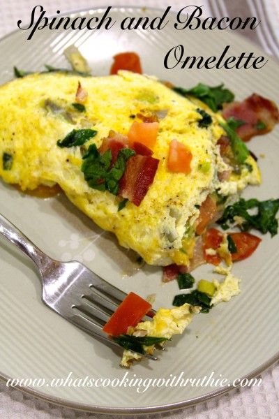 an omelet with spinach and bacon is on a plate next to a fork