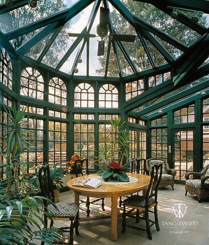 the inside of a green house with lots of windows and plants on the table in front of it