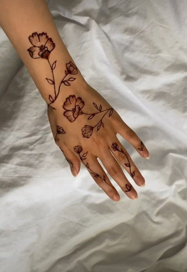 a woman's hand with tattoos on it and flowers painted on the palm,