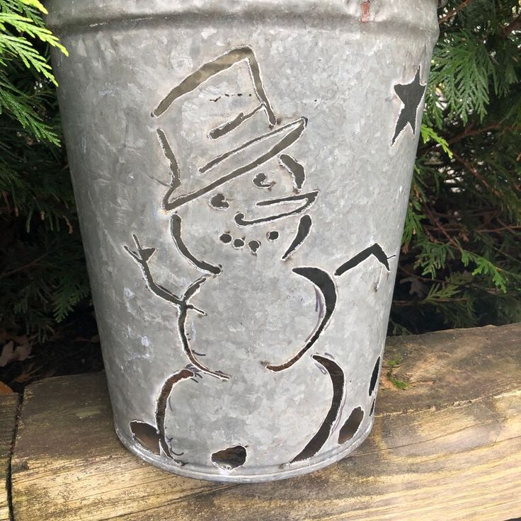 a metal bucket with a snowman drawn on it