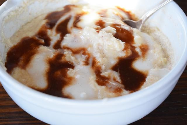 a white bowl filled with ice cream and caramel sauce on top of a wooden table