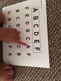 a person is pointing at the letters on a sheet of paper