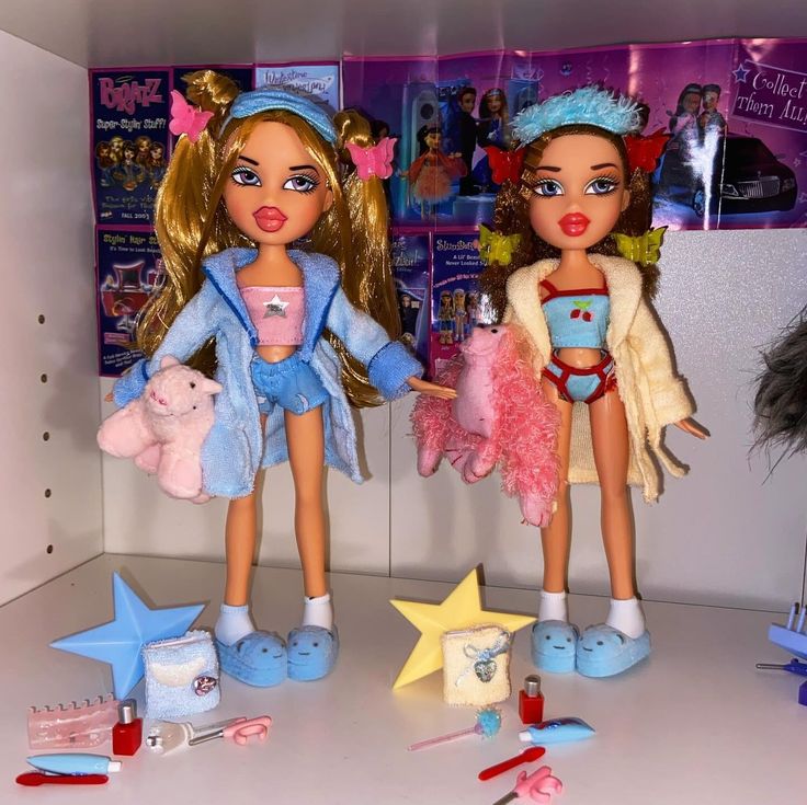 two dolls standing next to each other in a room with toys on the floor and wall behind them