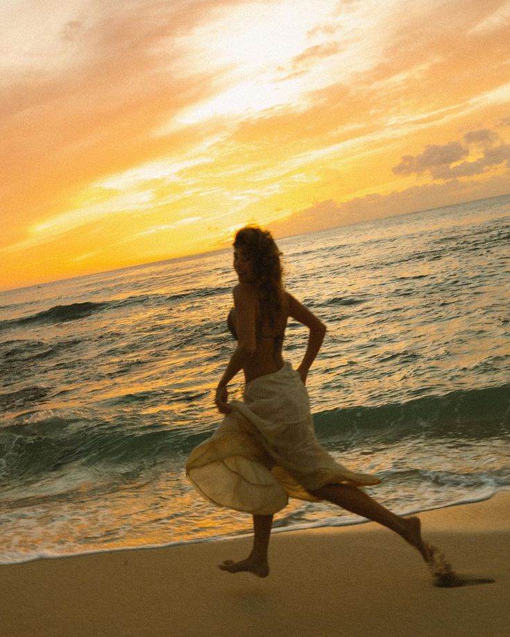 a woman running on the beach at sunset