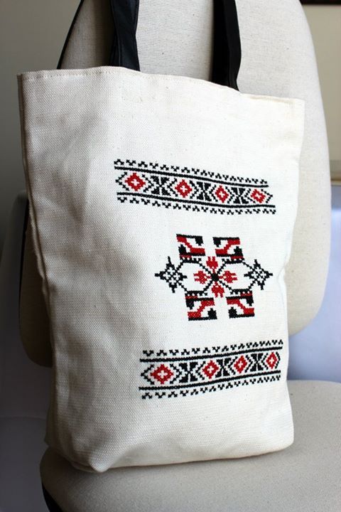 a white tote bag sitting on top of a chair next to a black handle