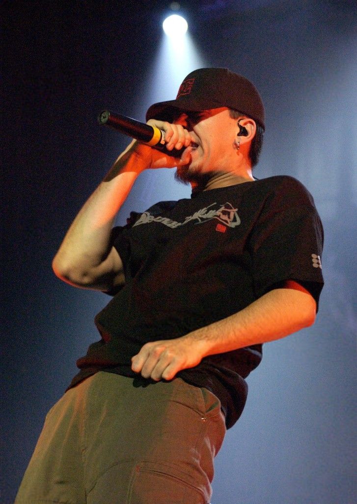 a man standing on top of a stage with a microphone in his hand and wearing a black shirt