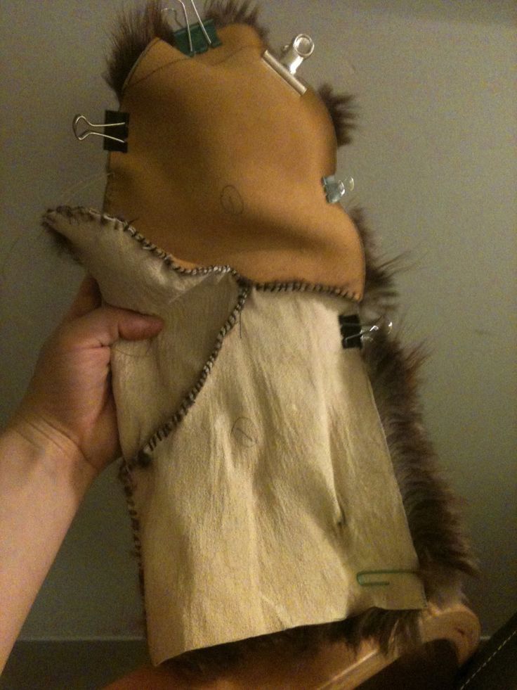 a person is holding up a cat made out of cloth and furs with scissors in it's mouth