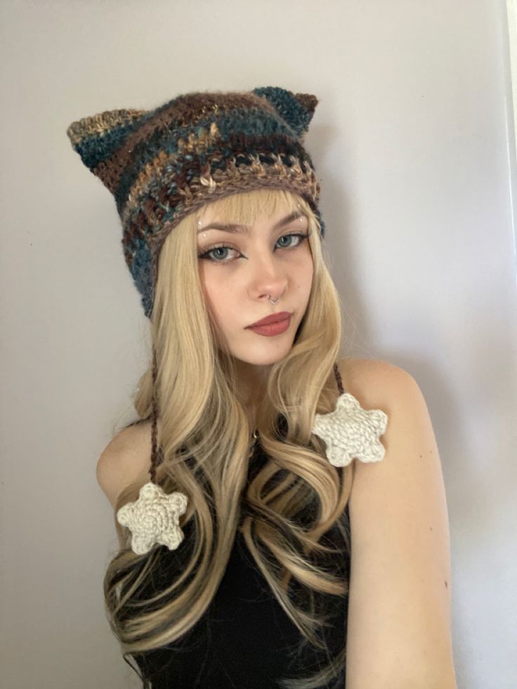 a woman with long blonde hair wearing a knitted cat ear flap hat and gloves