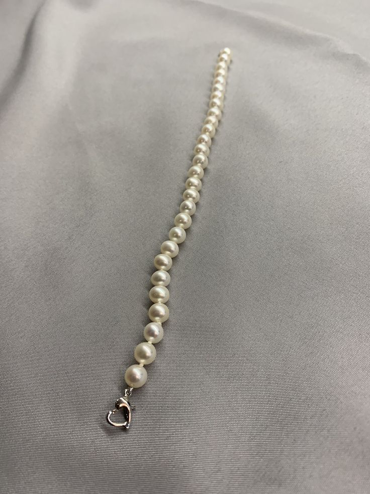 White Freshwater Pearl Bracelet. This bracelet features 28 White Freshwater Pearls AAA round to near round high luster 6.2mm with a heart clasp that is 18K white gold plate over 925 silver. The bracelet is 7 1/2 inches long measured laying flat. I hand knotted this bracelet using spectra thread. I use it instead of silk for my freshwater pearls. It does not stretch, hold oils, or break easily. It can also be gotten wet. I also like the heart clasp, they are easier to connect. We guarantee all of Classic Beaded Bracelets With Sterling Silver Clasp As Gift, Elegant Pearl Bracelet With Lobster Clasp And Round Beads, Elegant Pearl Bracelet With Lobster Clasp, Single Strand Sterling Silver Bracelet, Sterling Silver Single Strand Bracelet, Elegant Sterling Silver Bracelet With Clasp For Gift, Elegant Sterling Silver Bracelet With Clasp, Classic White Jewelry With Extender, White Pearl Bracelet With Lobster Clasp And Round Beads