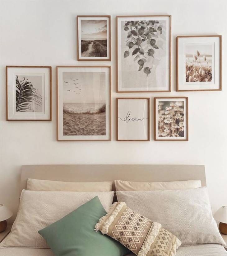 a white bed topped with lots of pillows and pictures on the wall above it's headboard