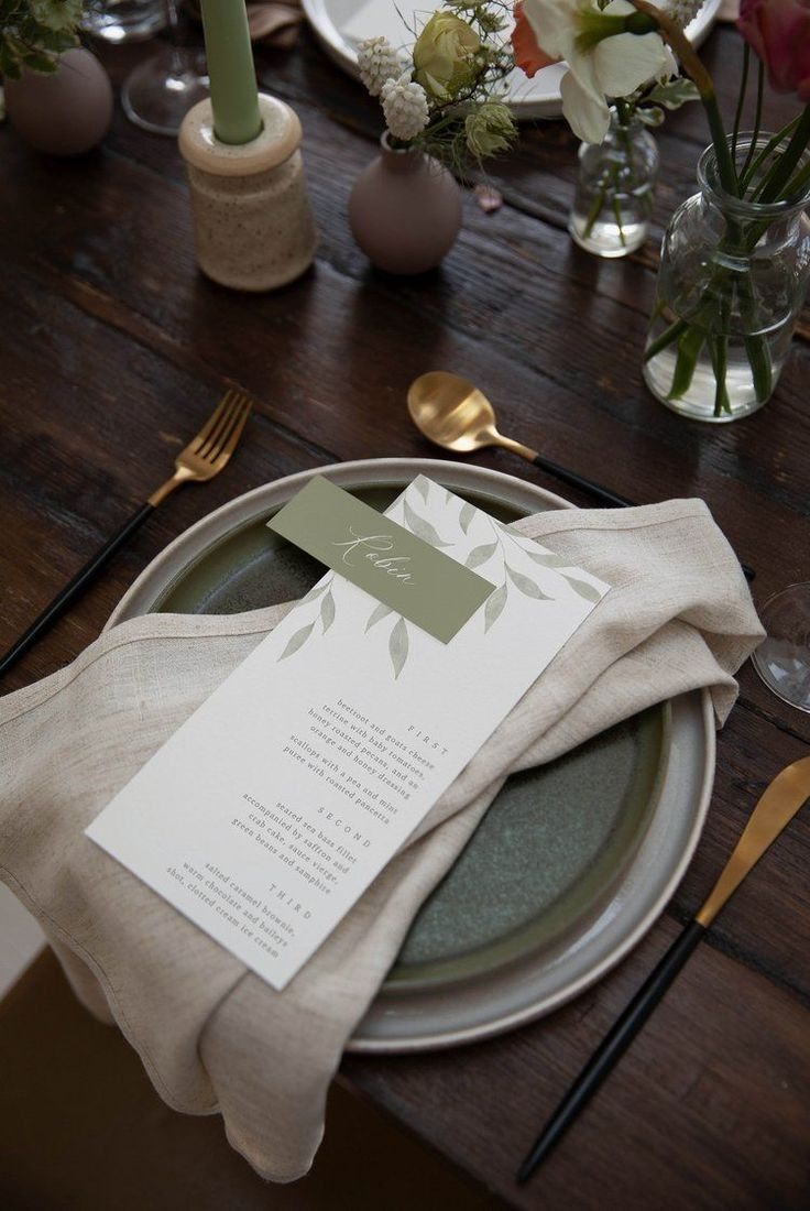 a table setting with place settings, napkins and flowers in vases on the table