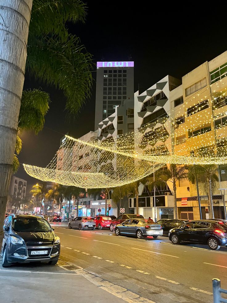 cars are parked on the street in front of buildings with christmas lights hanging from them