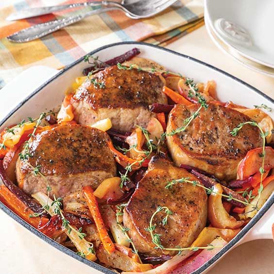 a pan filled with meat and vegetables on top of a table next to utensils