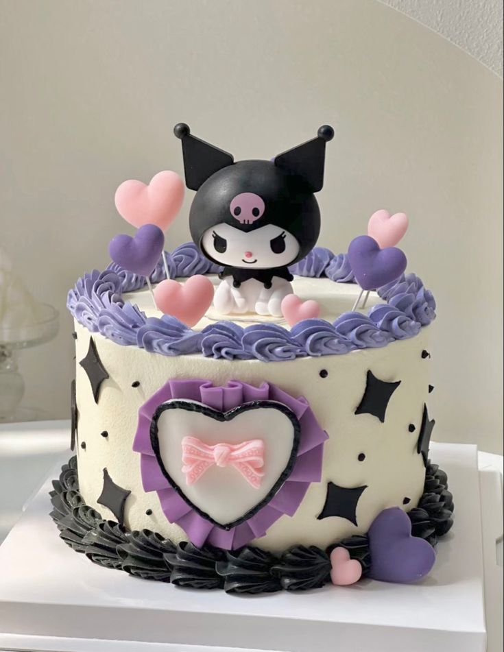 a cake decorated with purple and white icing has a cat figure on the top