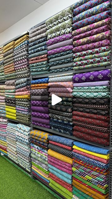 a display case filled with lots of different colored fabrics on top of green carpeted flooring