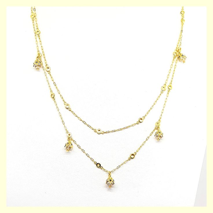 This beautiful necklace has a unique design - a very long chain that can be worn long or doubled, with the help of a toggle closure. It features tulip-shaped crystal drops set along half of the chain. Made of durable and beautiful 14kt gold-plated brass and enhanced with the finest European crystals. The full length is 42" or 20" when doubled. Made in the USA by La Vie Parisienne Gold Crystal Necklaces With Delicate Chain, Gold Crystal Necklace With Adjustable Chain, Gold Dangle Crystal Necklaces, Gold Crystal Necklace With Delicate Chain, Delicate Gold Necklace With Crystal, Delicate Gold Crystal Necklace, Gold Crystal Lariat Necklace, Gold Cubic Zirconia Drop Necklace, Gold Dangle Jewelry With Double Chain