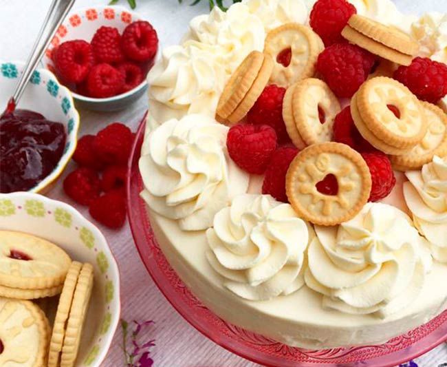 a cake with whipped cream, raspberries and cookies on the top is shown