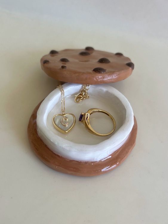 two pieces of jewelry sitting on top of a white table next to each other,