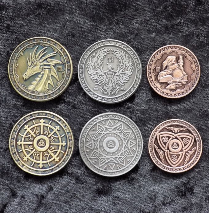 six different types of coins sitting on top of a black cloth covered surface, each with an image of a dragon in the center