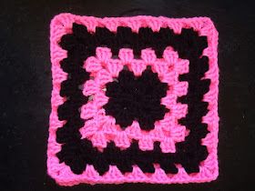 a pink and black square is shown on a table with a crochet pattern