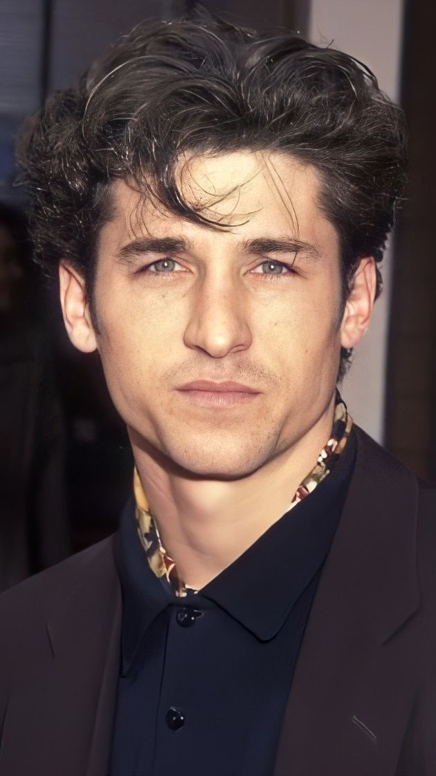 a close up of a person wearing a suit and tie with his hair in the air