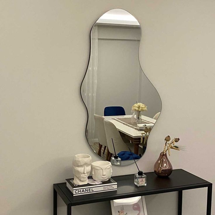 a mirror sitting on top of a black table next to a vase with flowers in it