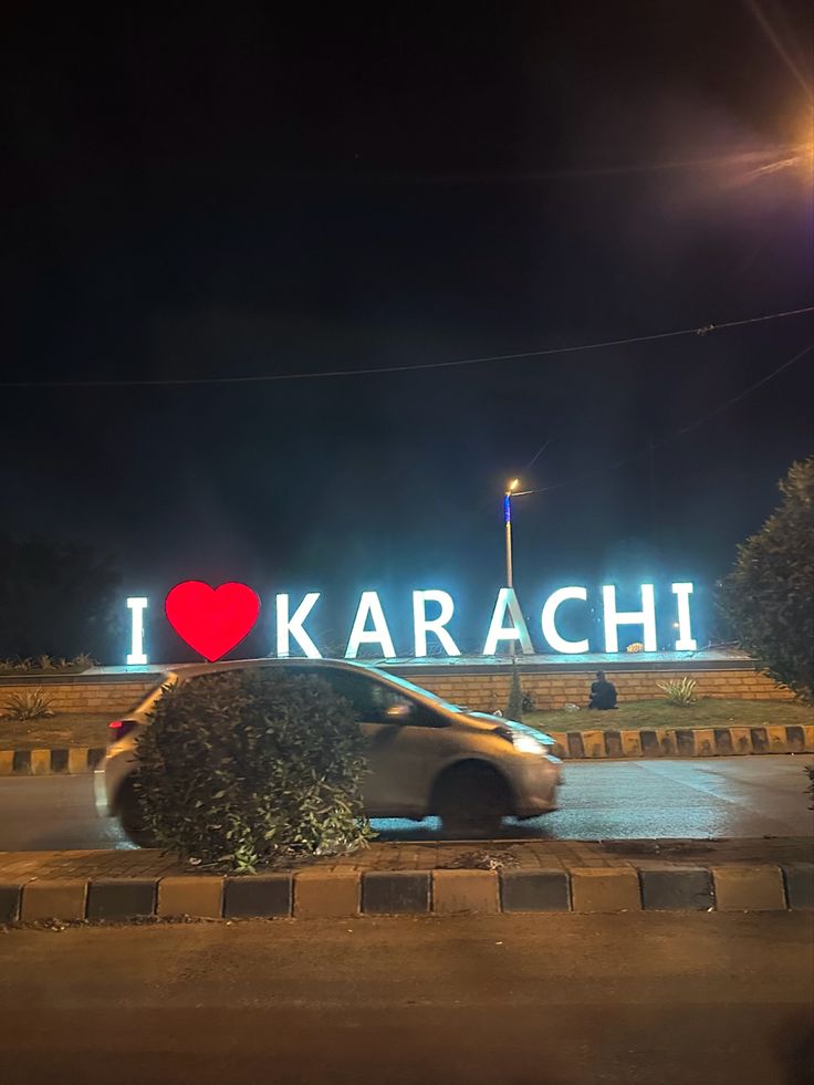 a car is parked in front of the i love karaci sign at night